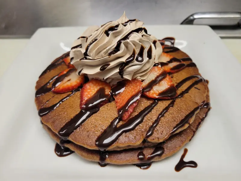 Pancakes with chocolate drizzle, strawberries and whipped cream