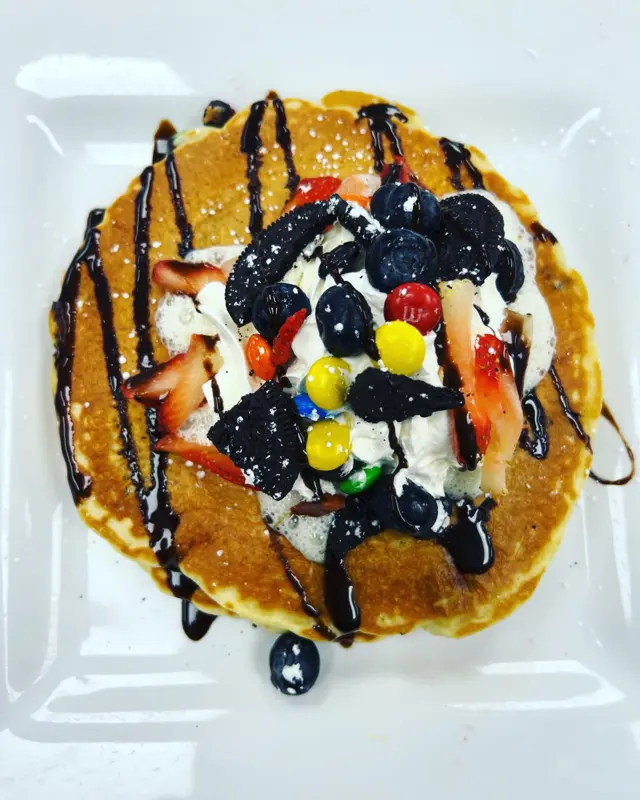 Pancake with whipped cream, candy, cookies and chocolate drizzle
