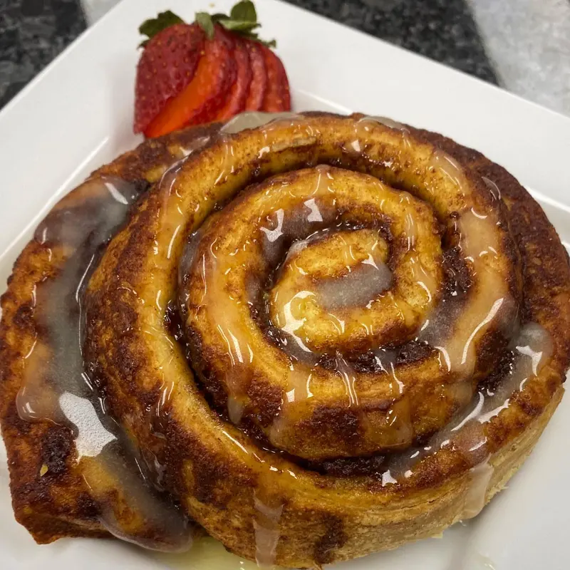 Warm glazed cinnamon roll with a strawberry