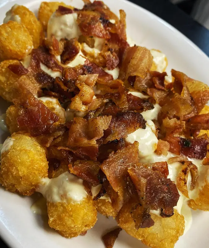 Tater tots piled with bacon and cheese
